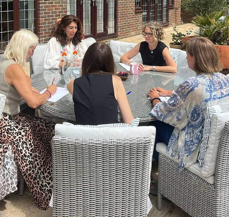 Marina with a client group around her garden table