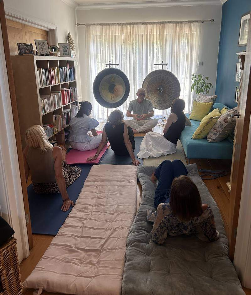 A small group sitting on mats around two gongs