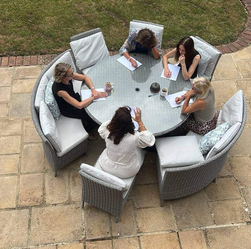 A small group writing around a garden table, seen from above