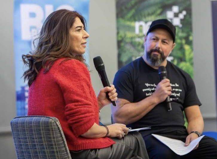 Marina speaking on stage with a microphone during a panel conversation